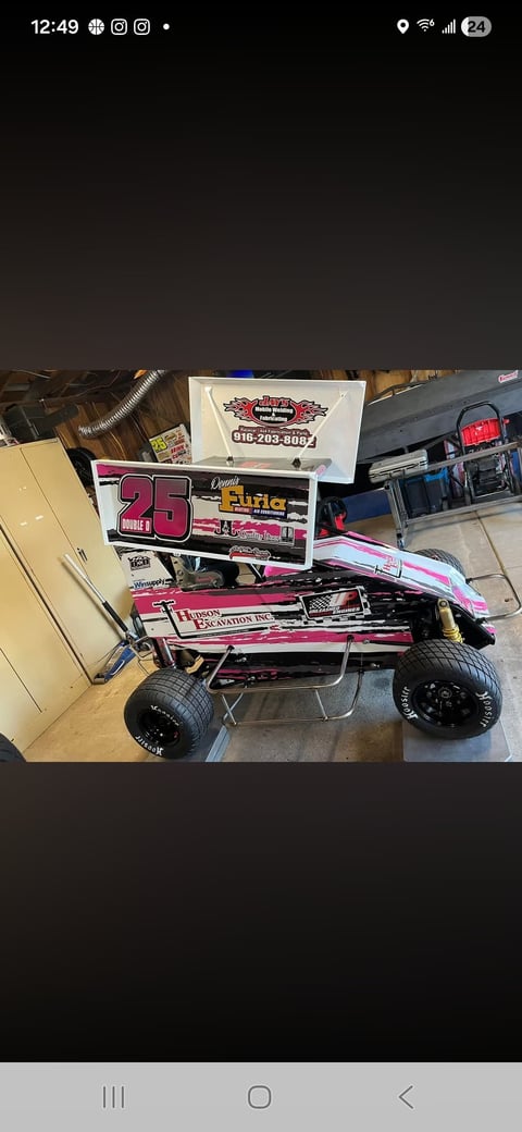 Pink and white sprint car with number 25 displayed indoors, featuring racing decals and sponsor logos